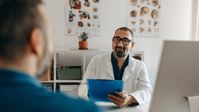 A doctor holding a chart is talking to his patient.